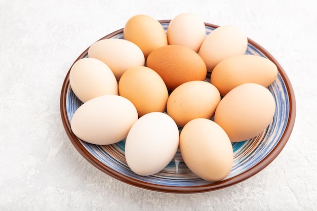 Montón de huevos de colores en un plato sobre una vista lateral de fondo de hormigón gris