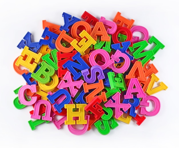 Montón de letras del alfabeto de colores de plástico sobre un blanco