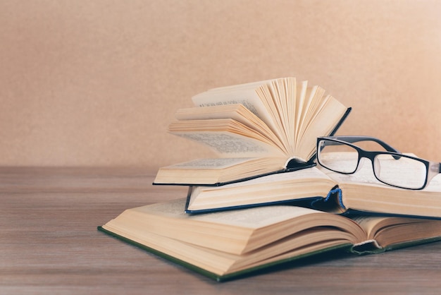 Montón de libros y anteojos sobre una mesa de madera de cerca