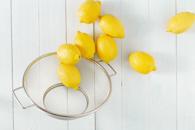 Montón de limones en colador sobre una mesa de madera vista superior