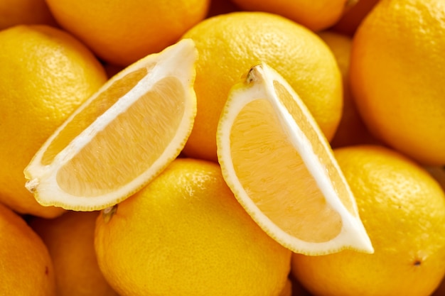 Montón de limones frescos en el mercado de alimentos orgánicos. Un limón cortado