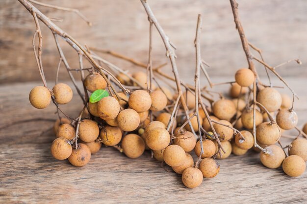 Montón de Longan y Peel muestran que la carne blanca con semilla negra se colocó sobre un fondo de madera