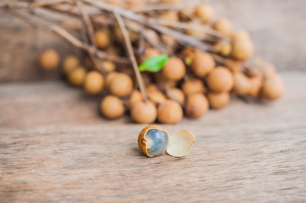 Montón de Longan y Peel muestran que la carne blanca con semilla negra se colocó sobre un fondo de madera