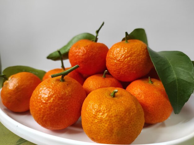 Montón de mandarinas en un plato blanco.