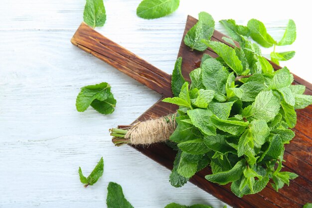 Montón de menta fresca y tablero de madera en la mesa