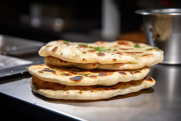 Montón de nan recién horneado y pan de ajo en la mesa de aluminio con una cocción perfecta