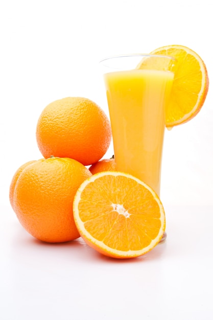 Montón de naranjas cerca de un vaso de jugo de naranja