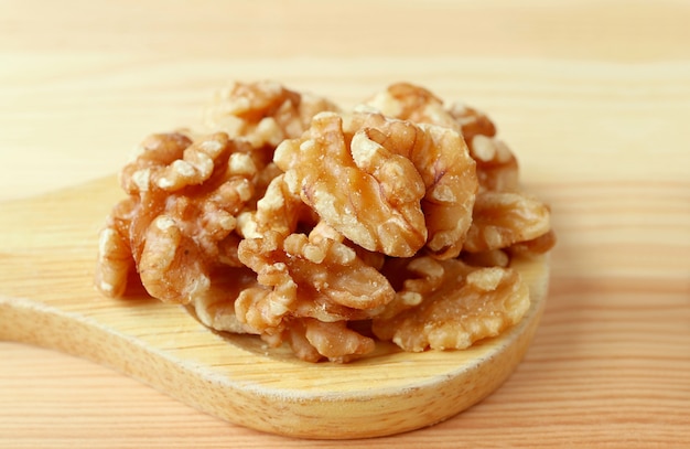 Montón de nueces en una cuchara de madera aislado en la mesa de madera