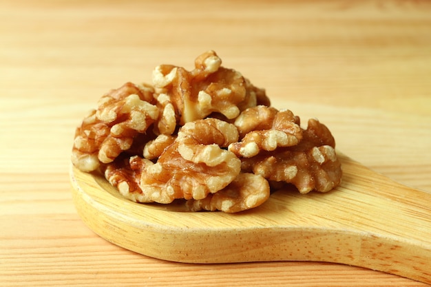 Montón de nueces en una cuchara de madera sobre mesa de madera