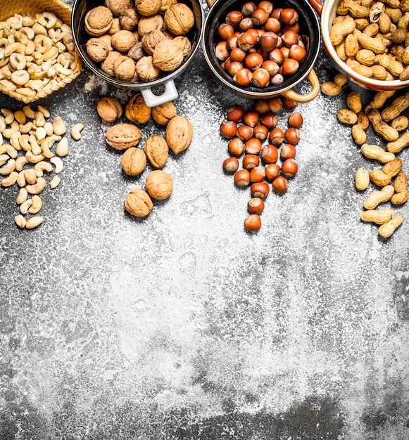 Un montón de nueces en diferentes cuencos sobre fondo rústico