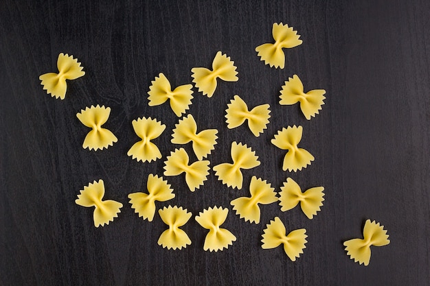 Un montón de pasta farfalle sobre fondo negro oscuro