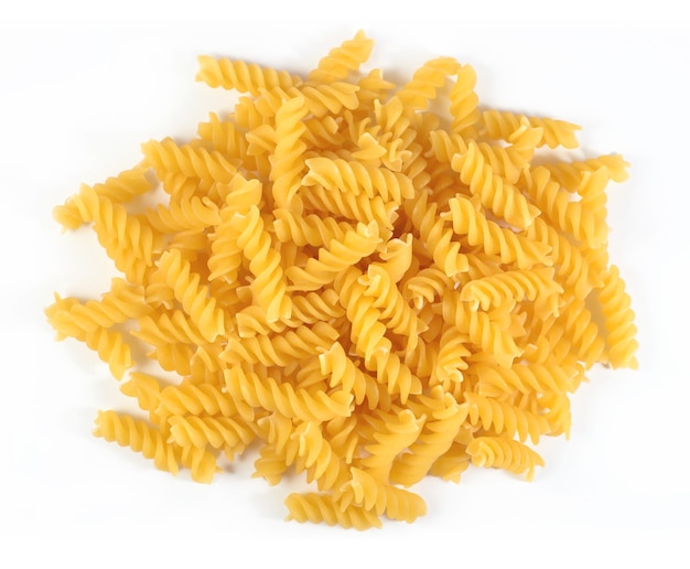 Montón de pasta italiana sin cocer fusilli sobre un fondo blanco.