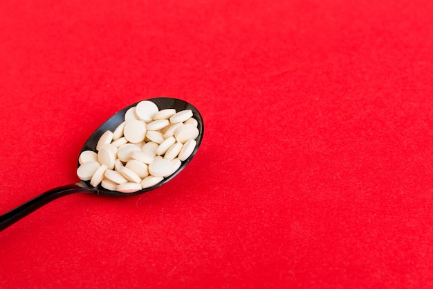 Montón de pastillas blancas sobre fondo de color Tabletas esparcidas sobre una mesa Montón de cápsula de gelatina blanda roja Concepto de vitaminas y suplementos dietéticos