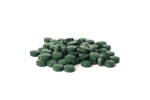 Montón de pastillas de espirulina aislado sobre fondo blanco.