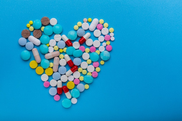 Un montón de pastillas en forma de corazón sobre un fondo azul como símbolo de tratamiento para proteger el corazón