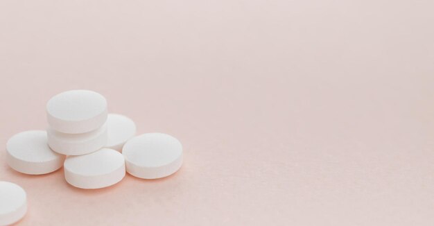 Montón de pastillas redondas blancas sobre fondo rosa con espacio de copia Concepto de atención médica