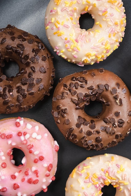 Un montón de pequeños donuts con glaseado de chocolate y rosa blanco en un plato negro