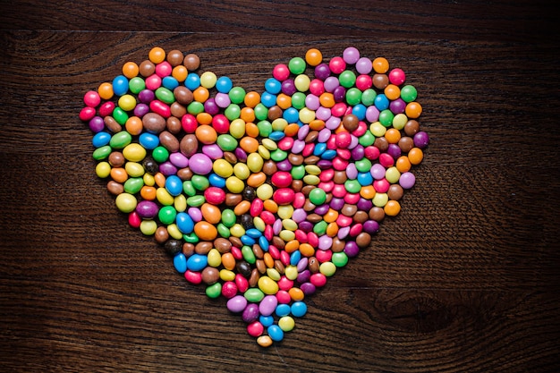 Un montón de pequeños y sabrosos dulces clorados de chocolate sobre fondo de madera