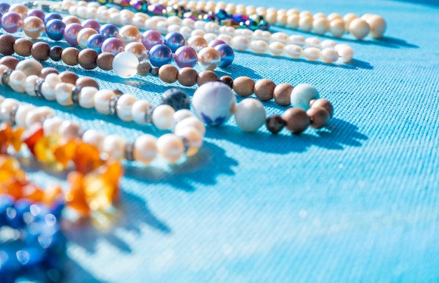 Montón de perlas de joyería de colores brillantes sobre un fondo azul Collar de cuentas de gemas diferentes Collar de joya patrón de moda moderno o espacio de copia de textura