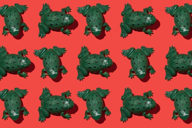 Foto un montón de ranas de juguete verdes con un fondo rojo