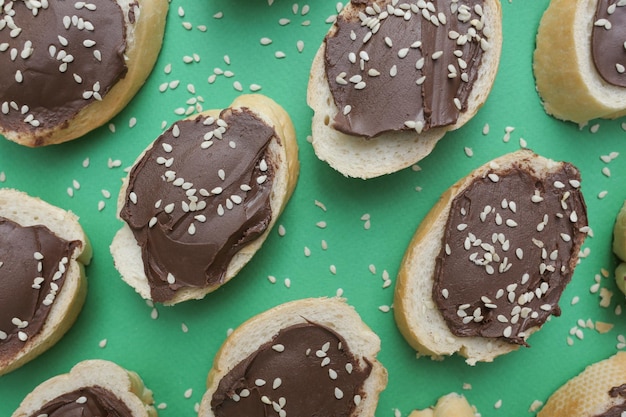 Un montón de rebanadas de pan blanco untadas con deliciosa pasta de chocolate sobre un fondo verde