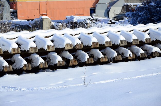 Un montón de rieles viejos y traviesas se apilan en un almacén ferroviario en invierno.