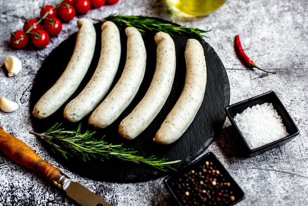 Un montón de salchichas en un plato negro con especias y hierbas.