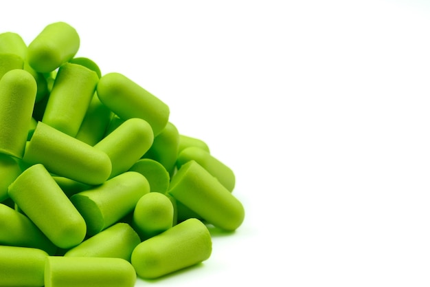 Un montón de tapones para los oídos de color verde claro sobre un fondo blancoCloseupSoft foam earplug