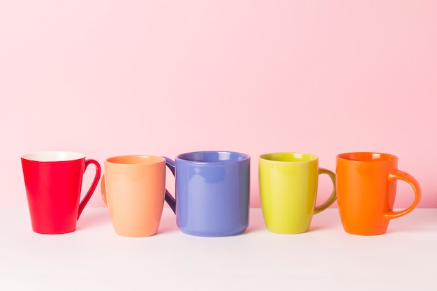 Un montón de tazas multicolores de café o té sobre un fondo rosa. El concepto de una compañía amigable, una familia numerosa, reunirse con amigos para una taza de té o café.