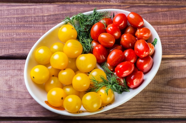 Montón de tomates cherry rojos y amarillos con eneldo en un tazón