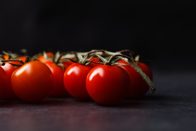 Montón de tomates cherry sobre fondo oscuro