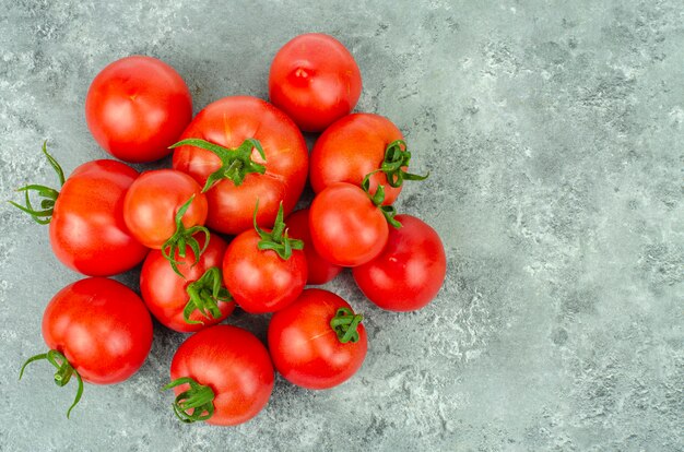 Montón de tomates maduros sobre fondo azul grisáceo. Foto de estudio.