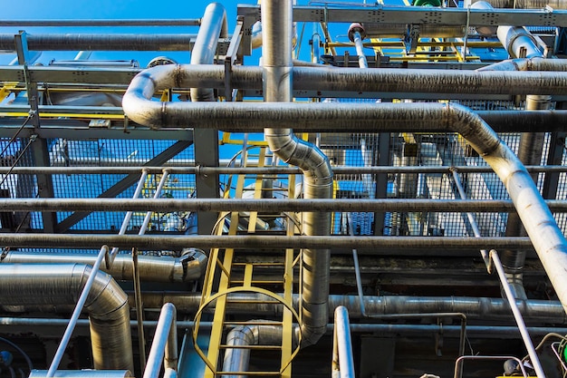 Un montón de tubos de metal se encuentran en una planta de procesamiento de gas contra el cielo azul