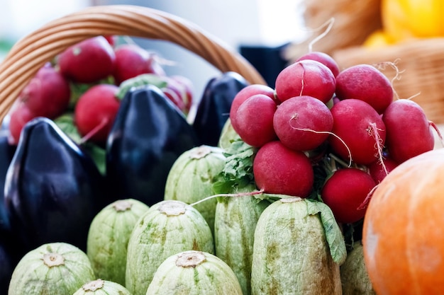 Un montón de tuétanos de rábanos rojos crudos y calabacín en una cesta de mimbre en una feria de pueblo Concepto de agricultura y alimentación rural