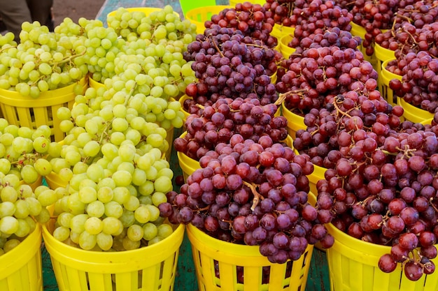 Un montón de uvas blancas y rojas orgánicas frescas en un mercado callejero