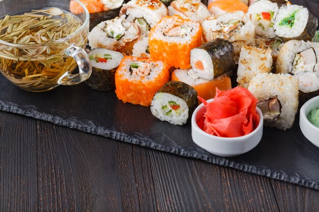 Montón de varios tipos de sushi servido en piedra negra