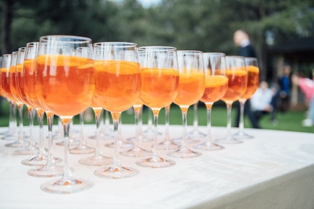 Un montón de vasos con jugo de manzana y naranja en la mesa del buffet.