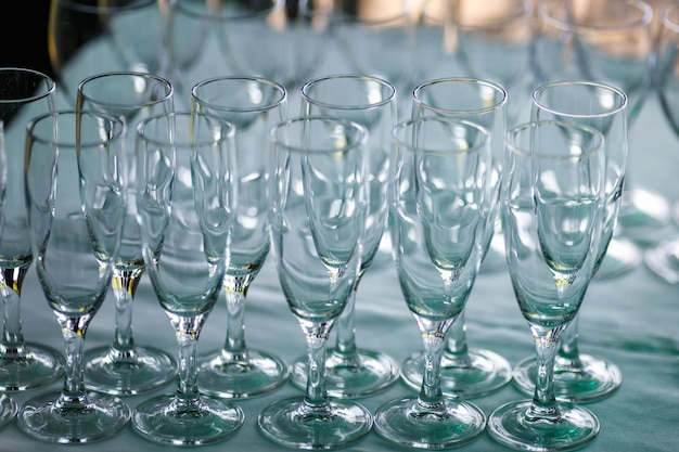 Un montón de vasos vacíos en la mesa de la fiesta de recepción Cierre en la fila de vasos prepárese para el servicio para la cena