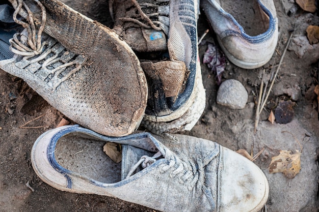 Un montón de zapatos viejos y sucios yace en el suelo. Zapatos gastados. Concepto de pobreza y miseria.