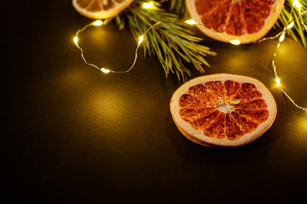 Moody vacaciones creativas Navidad Año Nuevo alimentos frutas con pomelo seco, kiwi, naranja y limón con rama de abeto con cálidas luces led, ángulo de visión, espacio de copia