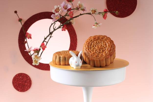 Mooncake auf hellrosa Hintergrund mit rosa Blume. Konzept-Mond-Kuchen auf Mid Autumn Festival. Mooncake Beliebt als Kue Bulan.