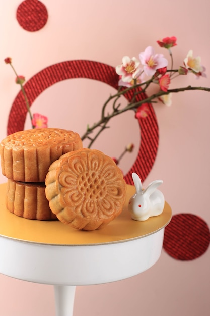 Mooncake auf hellrosa Hintergrund mit rosa Blume. Konzept-Mond-Kuchen auf Mid Autumn Festival. Mooncake Beliebt als Kue Bulan.