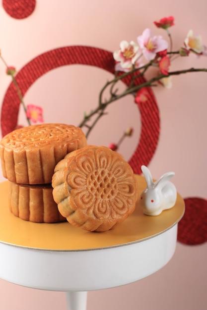 Mooncake auf hellrosa Hintergrund mit rosa Blume. Konzept-Mond-Kuchen auf Mid Autumn Festival. Mooncake Beliebt als Kue Bulan.