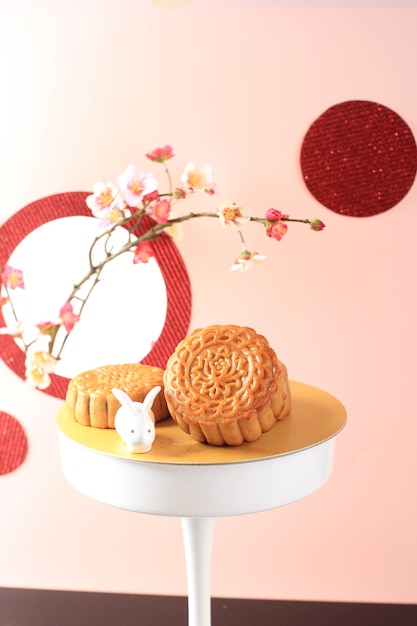Mooncake em fundo rosa claro com flor rosa. bolo de lua de conceito em mid autumn festival. mooncake popular como kue bulan.