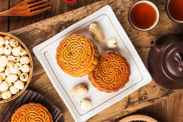 Foto mooncakes tradicionais na configuração de mesa com uma xícara de chá.