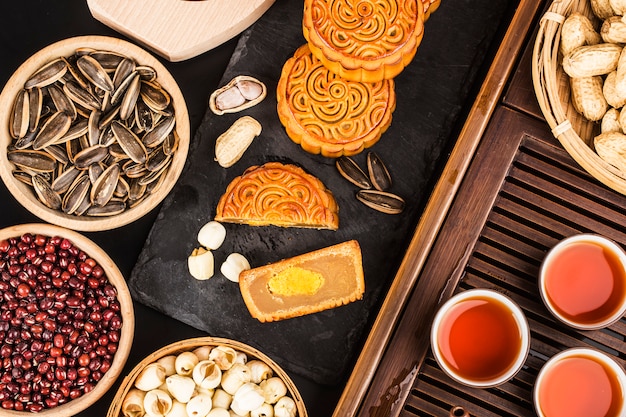 Foto mooncakes tradicionais na configuração de mesa com uma xícara de chá.