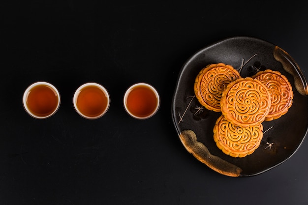 Mooncakes tradicionais no ajuste da tabela com xícara de chá.