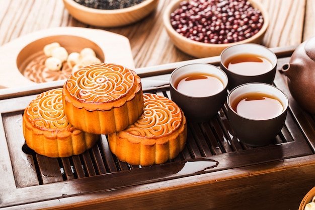 Mooncakes tradicionais no ajuste da tabela com xícara de chá.