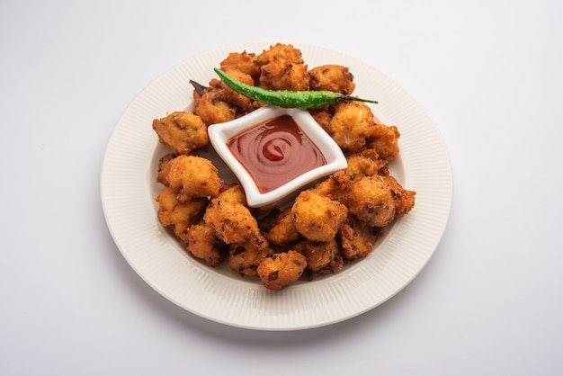 Moong Dal Vada o mungode Pakoda, Dalwada, Pakora o Mungdal Bhajiya o Buñuelos de gramo amarillo servidos con salsa de tomate