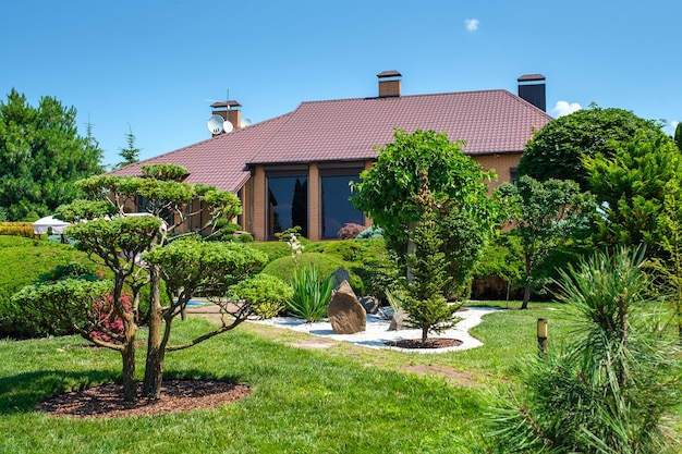 Moradia de estilo europeu com piscina e jardim com arbustos e árvores bem aparados na frente da casa. Projeto paisagístico. Foto de alta qualidade